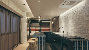 A modern kitchen with a central island, wooden stools, and a brick wall backsplash. - illi Lay Shibuya-Ebisu (Tokyo)
