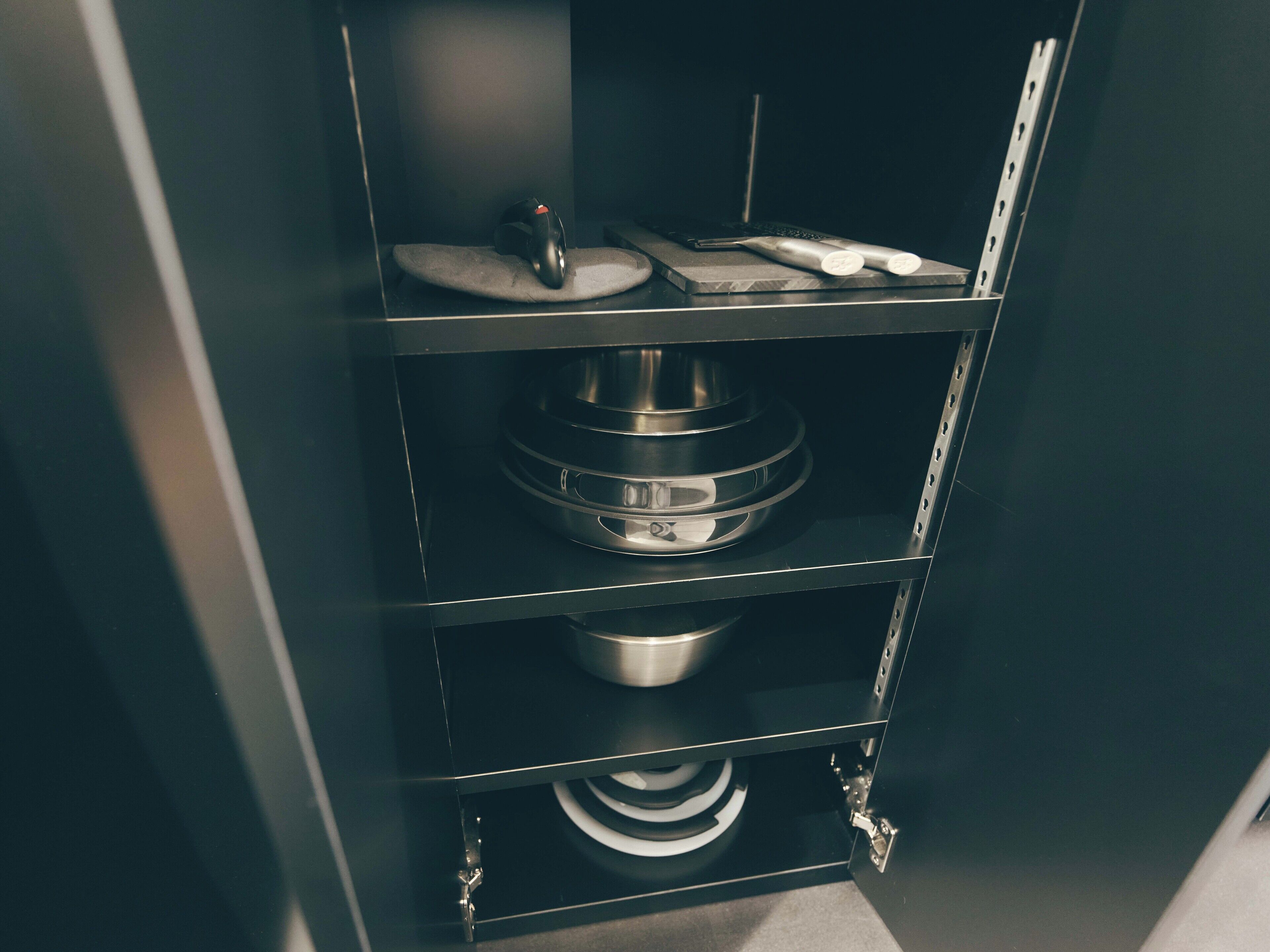 A kitchen with a black countertop, a stainless steel mixing bowl, and a white appliance.