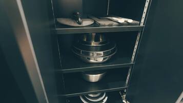 A kitchen with a black countertop, a stainless steel mixing bowl, and a white appliance.
