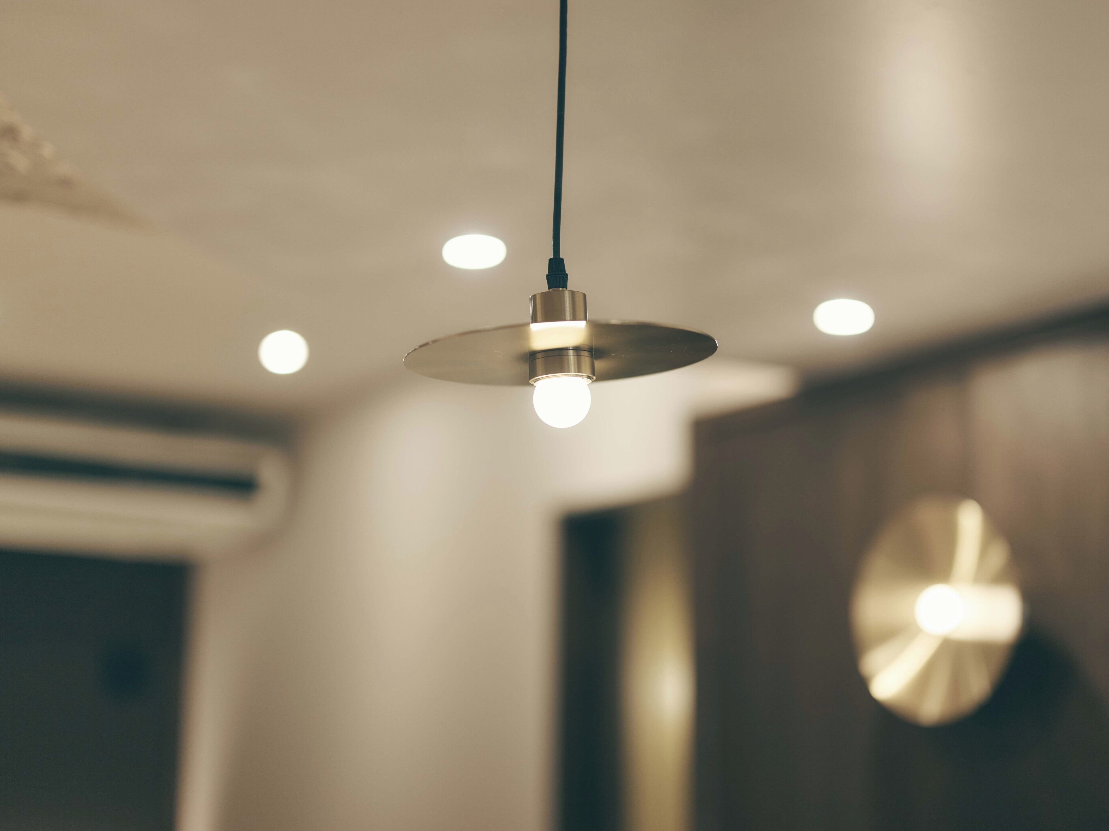 A pendant light fixture with a spherical shade and a visible bulb, hanging from a black cord.