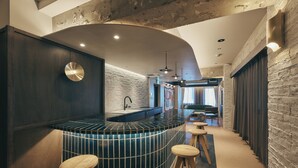 A modern bar area with a curved counter, stools, and a brick wall. - illi Lay Shibuya-Ebisu (Tokyo)