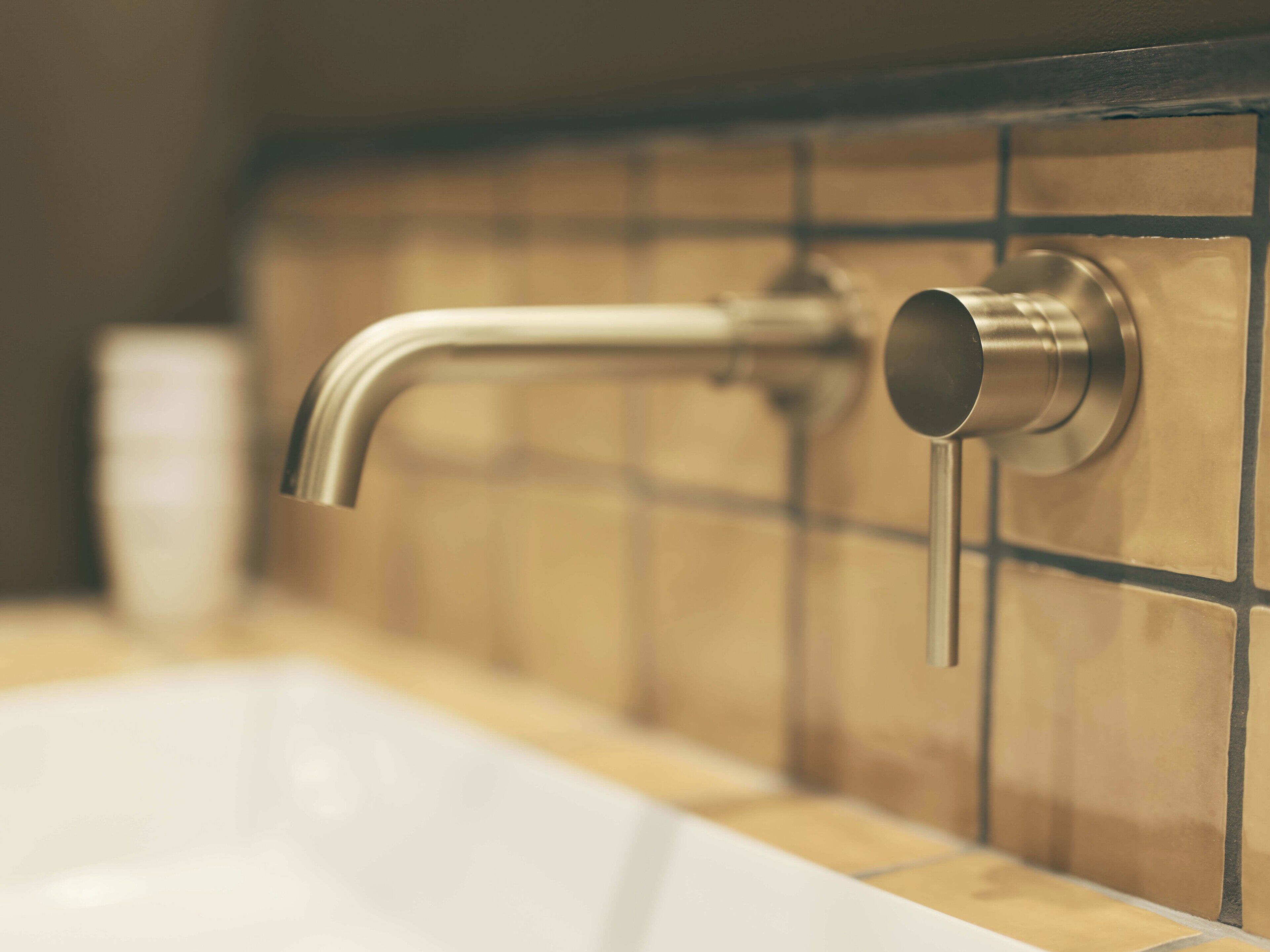 A bathroom with a white sink and a metallic faucet.