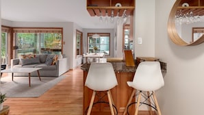 Une cuisine moderne avec un îlot central en bois, des tabourets de bar et un grand miroir.