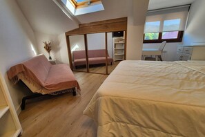 Een slaapkamer met een bed, een bank, een bureau en een kledingkast.