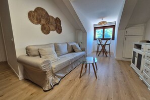 Una sala de estar con un sofá, una mesa de centro de vidrio y un comedor con mesa y sillas.
