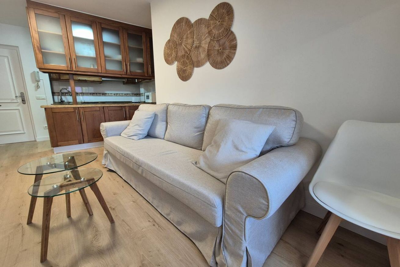 A living room with a sofa, a glass coffee table, wooden cabinets, and a wall decoration.