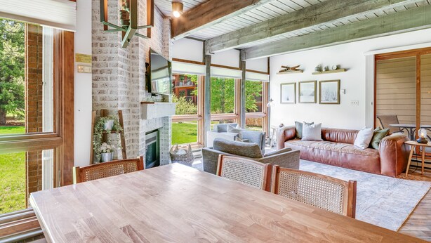 A spacious living area with a wooden dining table, a fireplace, and a comfortable seating area with a leather sofa and cushions.