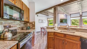 A modern kitchen with wooden cabinets, a stainless steel microwave, and a large island with a sink.