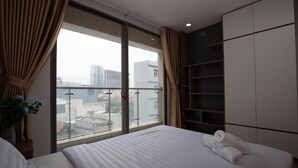 A hotel room with a large bed, a wardrobe, and a view of the city through a large window. - Comfor apartment stay in HCM (Ho Chi Minh City)