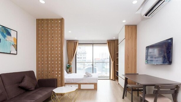 A modern hotel room with a sofa, a small round table, a bed, a dining table with chairs, a TV, and a large window with curtains. - Comfor apartment stay in HCM (Ho Chi Minh City)