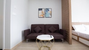 A modern room with a brown sofa, a white coffee table, and two abstract paintings on the wall. - Comfor apartment stay in HCM (Ho Chi Minh City)