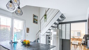 Eine moderne Küche mit einer großen Kochinsel, Edelstahlgeräten und einer Treppe, die in eine obere Etage führt.