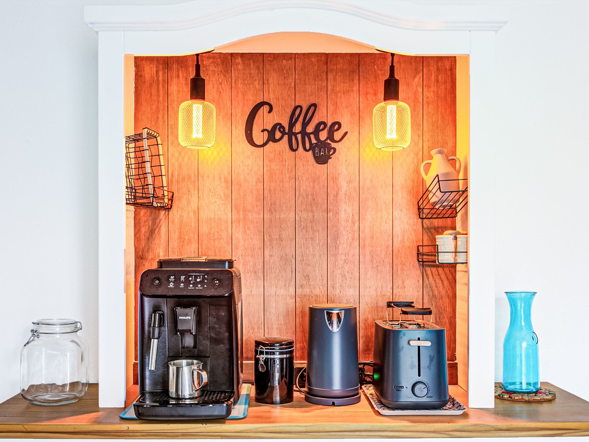 A coffee station with a coffee machine, a toaster, a kettle, and a coffee mug.