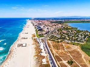 Vista aérea de una ciudad costera con playa, autopista y zonas residenciales.