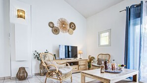 Ein modernes Wohnzimmer mit Flachbildfernseher, Korbmöbeln, Couchtisch und Wanddekoration.