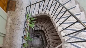 Un escalier en colimaçon avec une rampe en métal et un petit bac à fleurs contenant des plantes à sa base.