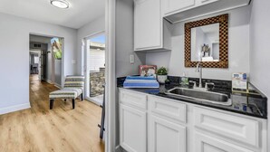 Una cocina moderna con muebles blancos, encimera negra y un reverso de espejo a cuadros.