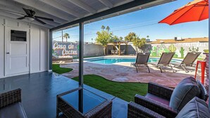 Zona de piscina con un porche cubierto, sillas de descanso y un letrero que dice "Casa de Cactus".