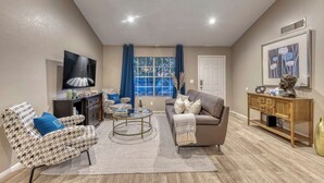 A living room with a sofa, armchair, coffee table, and a TV. - Blue Oasis with Private Heated Pool at NO COST (Tempe)