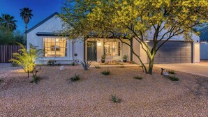 A modern house with a gravel driveway, a large tree in front, and a garage. - Blue Oasis with Private Heated Pool at NO COST (Tempe)