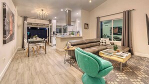 A modern living room with a sofa, a coffee table, and a dining area with chairs and a table.