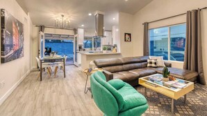 A modern living room with a sofa, a coffee table, and a dining area with a table and chairs.