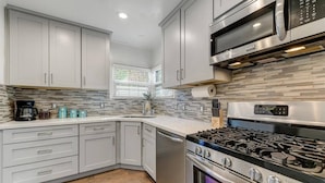 A modern kitchen with grey cabinets, a stainless steel stove, and a tiled backsplash. - Fabulous entertainers Paradise! Pool & Spa (Phoenix)