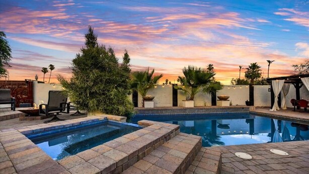 A pool area with a view of the sunset, surrounded by potted plants and outdoor furniture. - Fabulous entertainers Paradise! Pool & Spa (Phoenix)