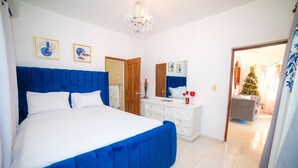 A bedroom with a large bed, a dresser, a mirror, and a chandelier. - Spacious and secure villa 5 minutes from the beach (Puerto Plata)