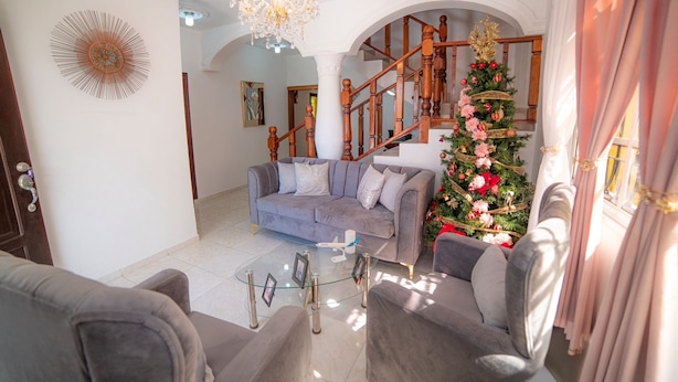 A living room with a grey sofa, a glass coffee table, and a Christmas tree. - Spacious and secure villa 5 minutes from the beach (Puerto Plata)