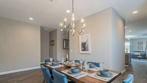 A dining area with a wooden table, blue chairs, and a chandelier.