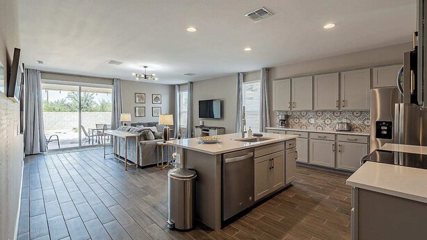 A modern kitchen with a central island, built-in appliances, and a dining area with a sofa and table.