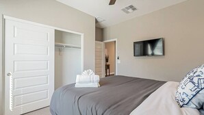 A bedroom with a bed, a TV mounted on the wall, and a closet with a door.