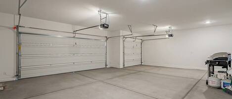 Eine saubere, leere Garage mit drei großen Garagentoren, Deckenbeleuchtung und einem Werkswagen mit Gasbehältern.
