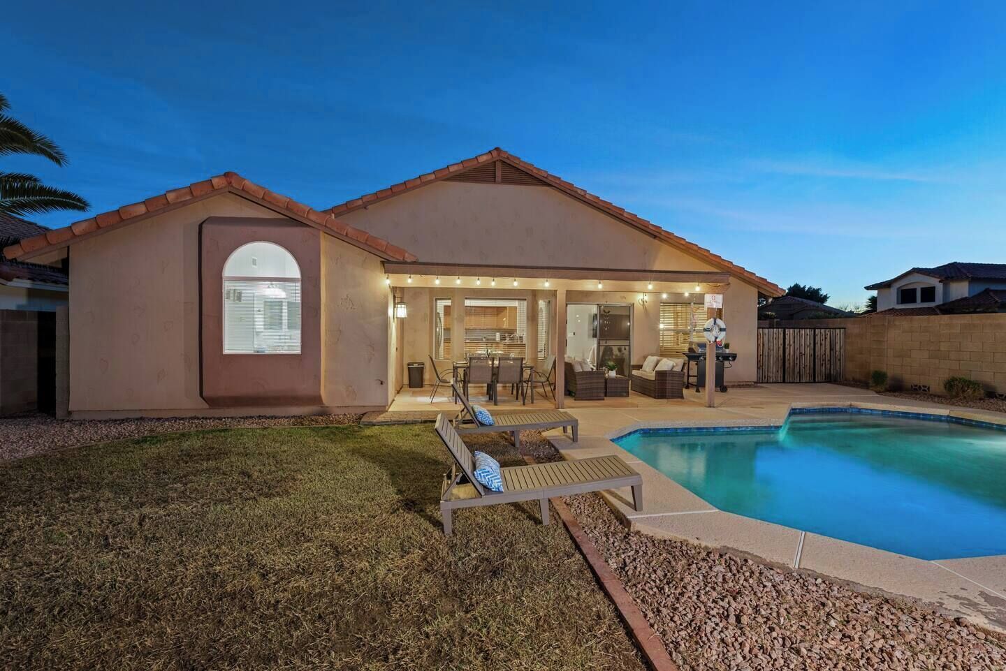 Une maison avec une piscine, un patio couvert et une cour arrière clôturée.