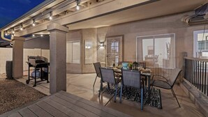 Un espace extérieur aménagé avec un patio, un barbecue, une table à manger et des chaises.