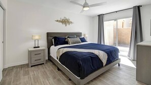 A modern bedroom with a bed, bedside tables, a ceiling fan, and a view of the outside. - The BEST Executive home in Palm Desert!4 Bedrooms (Palm Desert)
