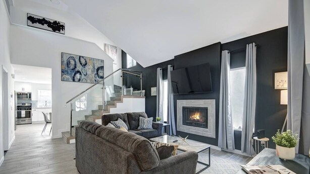 A modern living room with a grey sectional sofa, a fireplace, and a staircase leading to an upper level. - The BEST Executive home in Palm Desert!4 Bedrooms (Palm Desert)