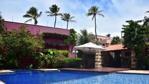A swimming pool with a tiled edge, surrounded by greenery and palm trees. - Charming apartment on Cumbuco Beach, Ceara, Brazil (Praia de Cumbuco Caucaia)