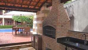 An outdoor patio with a brick oven, a sink, and a table with chairs. - Charming apartment on Cumbuco Beach, Ceara, Brazil (Praia de Cumbuco Caucaia)
