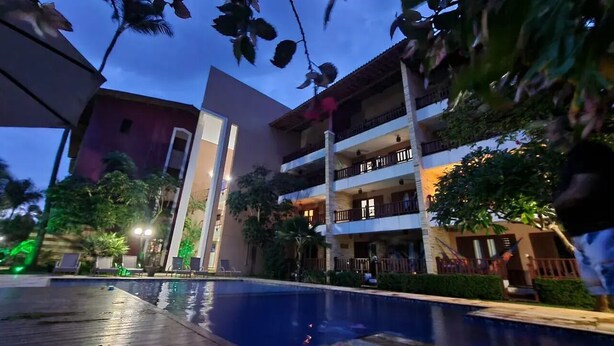 A hotel with a swimming pool, multiple balconies, and lush greenery. - Charming apartment on Cumbuco Beach, Ceara, Brazil (Praia de Cumbuco Caucaia)
