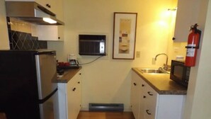 Cocina compacta con refrigerador, microondas y pileta.