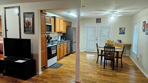 A modern kitchen with wooden cabinets, stainless steel appliances, and a dining area with a table and chairs.