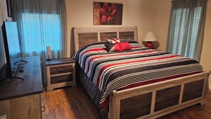 A bedroom with a bed, bedside table, lamp, and a ceiling fan.