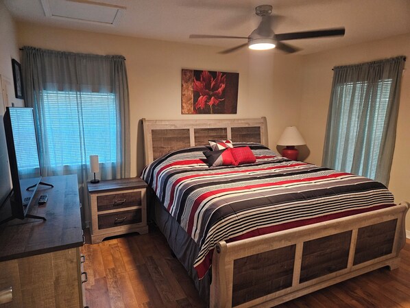Une chambre à coucher avec un lit, une table de chevet, une lampe et un ventilateur de plafond.