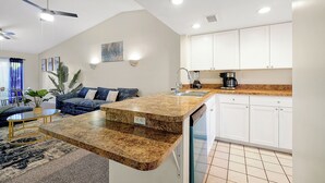 A compact kitchen with a built-in dishwasher, a dining area with a small table and chairs, and a ceiling fan. - Cozy 2-bedroom apartment in charming Orlando with AC, WiFi (Orlando)