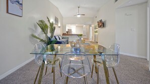 A dining area with a glass table and chairs, a ceiling fan, and a kitchen in the background. - Cozy 2-bedroom apartment in charming Orlando with AC, WiFi (Orlando)