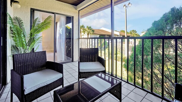 A balcony with wicker furniture, a glass table, and a view of the surrounding area. - Cozy 2-bedroom apartment in charming Orlando with AC, WiFi (Orlando)