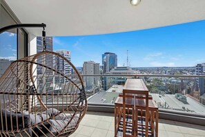 Un balcone con una sedia a dondolo e un tavolo in legno, con vista sulla città.