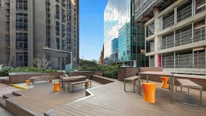 An outdoor deck with wooden flooring and orange seating. - Arcade In The Sky- Views, Games & Vibes (Brisbane City)